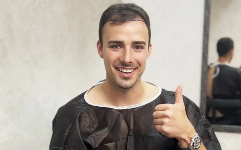 A Sapphire FUE patient smiles and gives a thumbs up before his surgery.